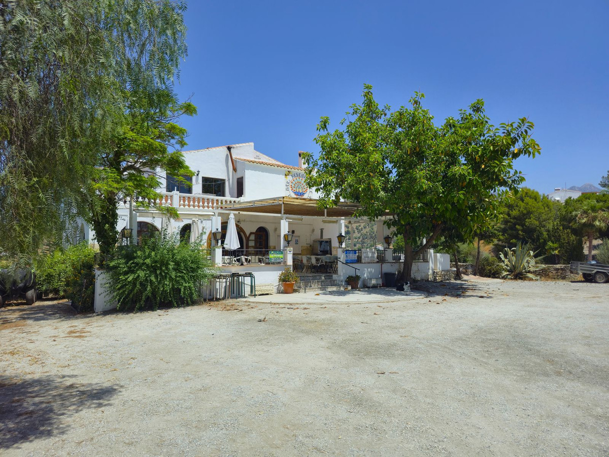 Exterieur van een Spaans wit gebouw met bomen en terras.