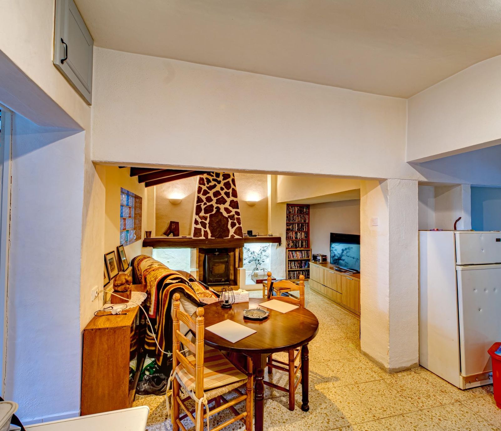 Rustieke woon-eetkamer met open haard en ronde tafel.