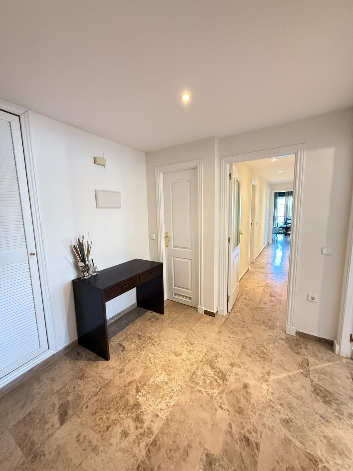 Hal interieur met bureau, garderobe en doorgang naar andere kamers.