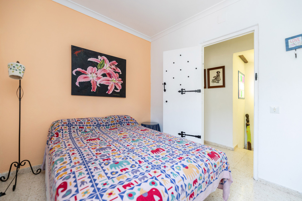 Gezellige slaapkamer met eclectisch decor, kleurrijk beddengoed en schilderij.