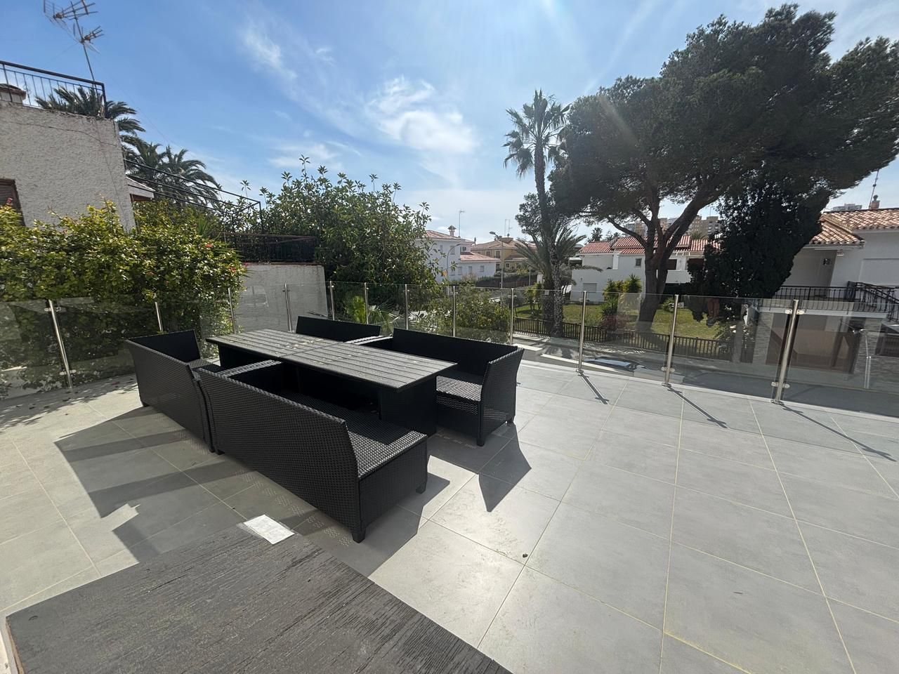 Terras met zwart wicker tuinmeubilair en uitzicht op de omgeving