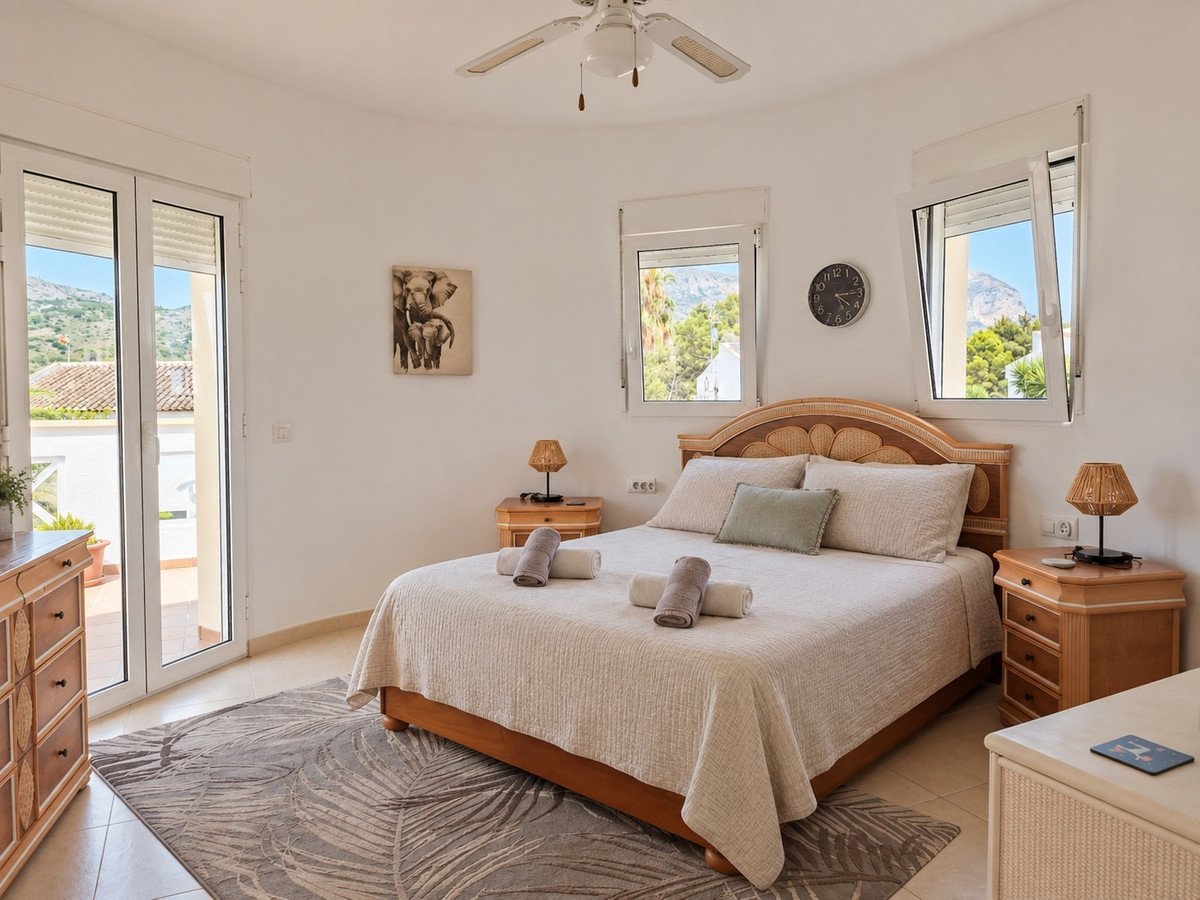 Bright bedroom with a king-size bed, mountain views from windows, and balcony access. Decorated with elephant art.