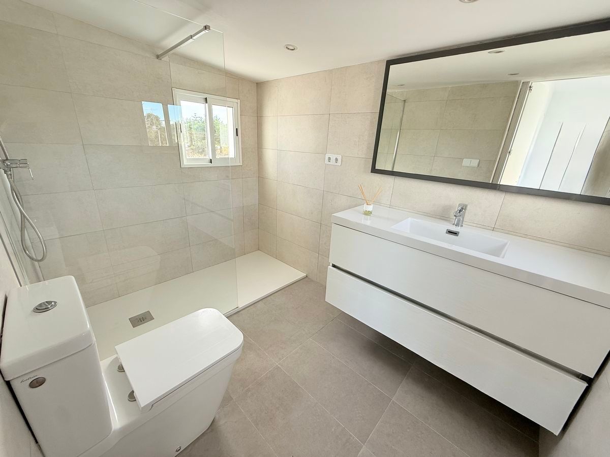 Moderne badkamer met witte armaturen en lichte tegels.