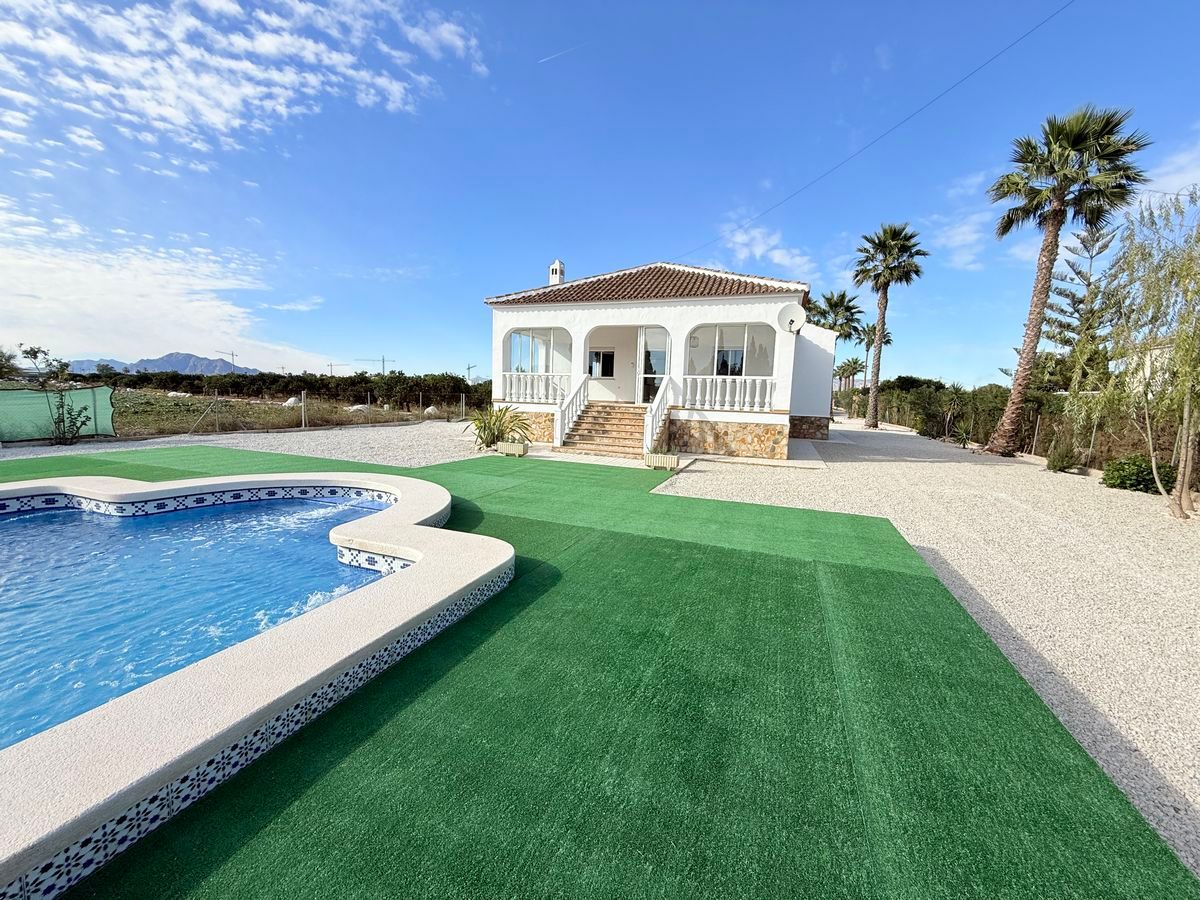 Witte Spaanse villa met zwembad en palmbomen.