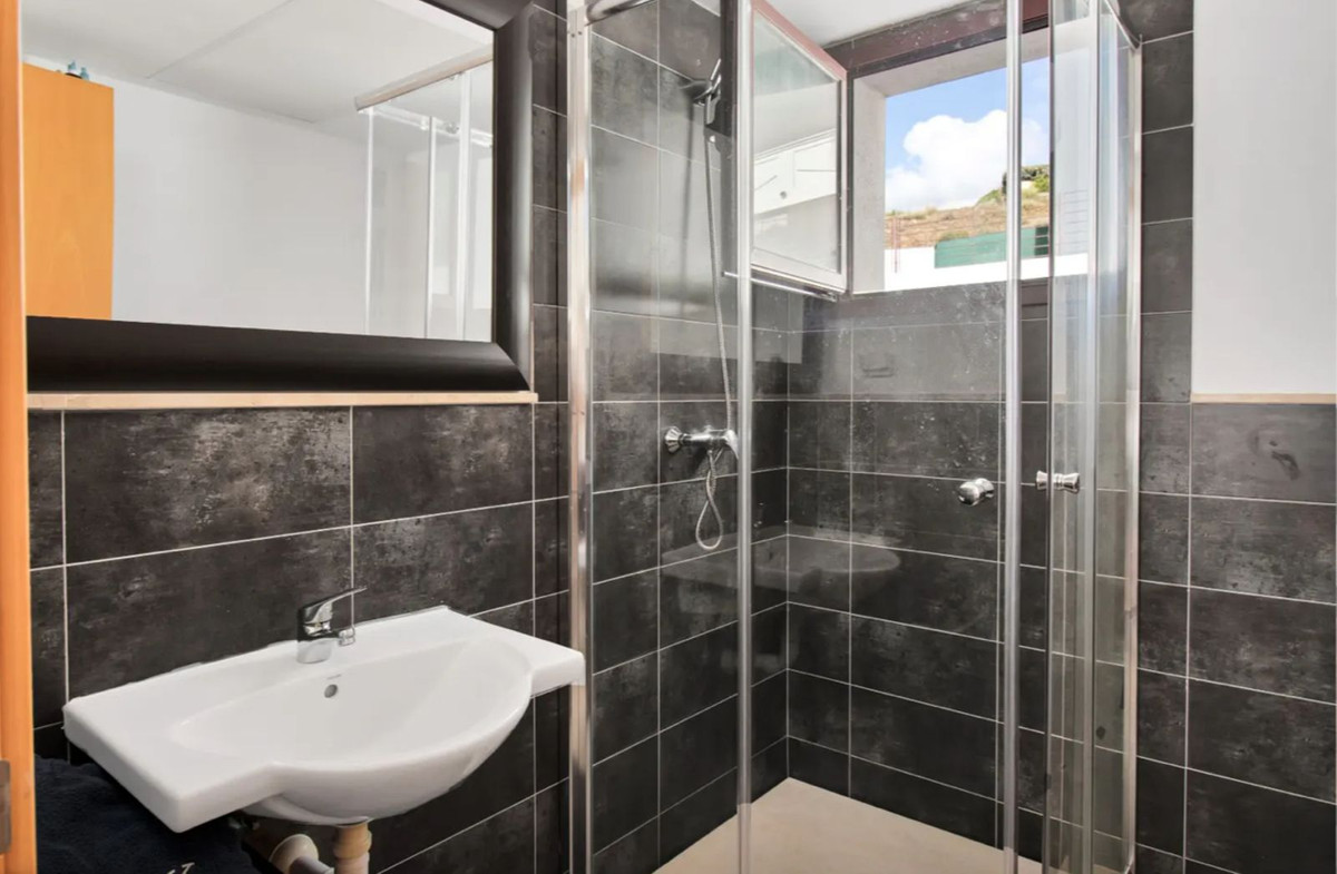 Moderne badkamer met donkere tegels en douchecabine.