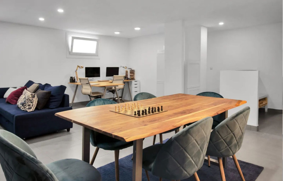 Moderne, multifunctionele woonruimte met eettafel, schaakbord en werkplekken.