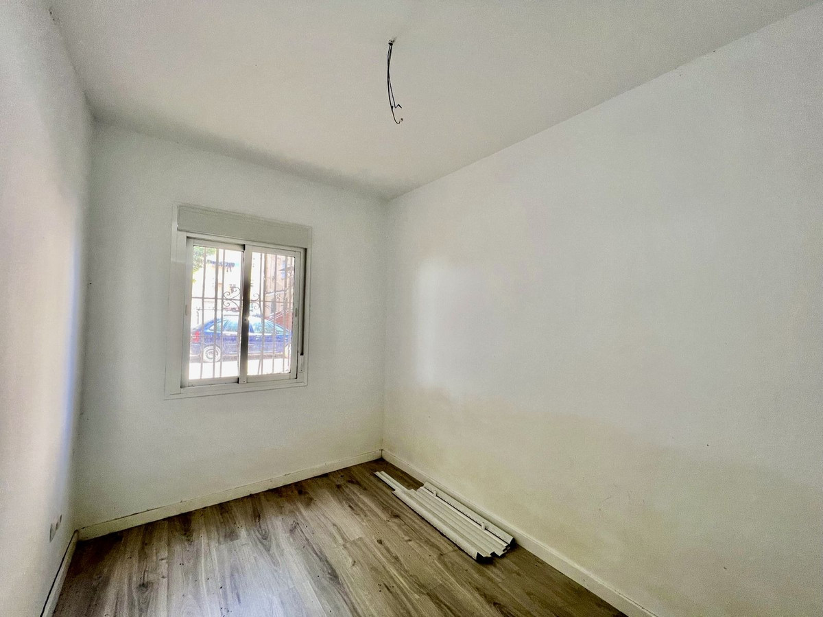 Lege kamer met raam en houten vloer, klaar voor renovatie.