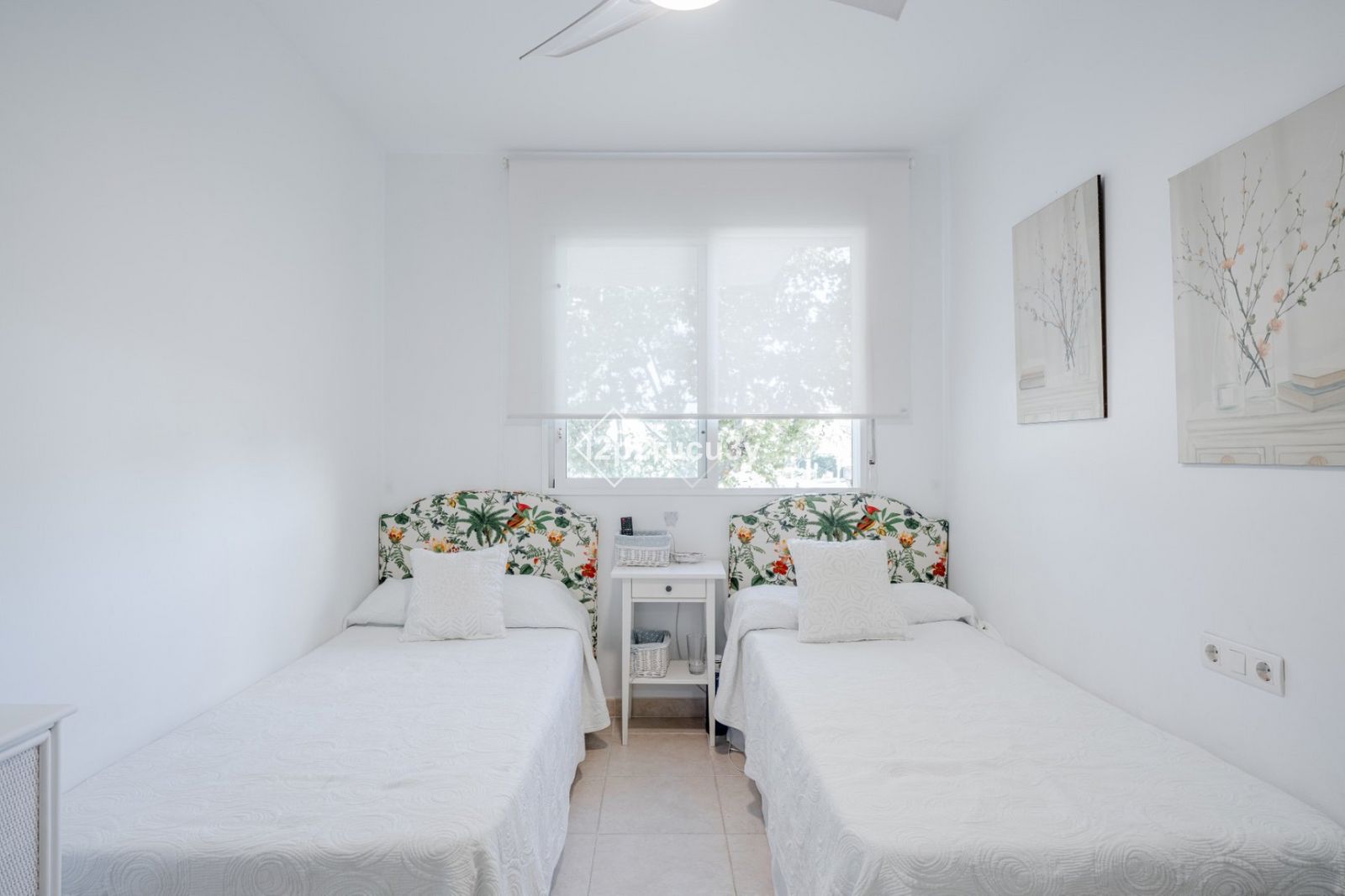 Witte slaapkamer met bloemen hoofdborden en witte bedden.