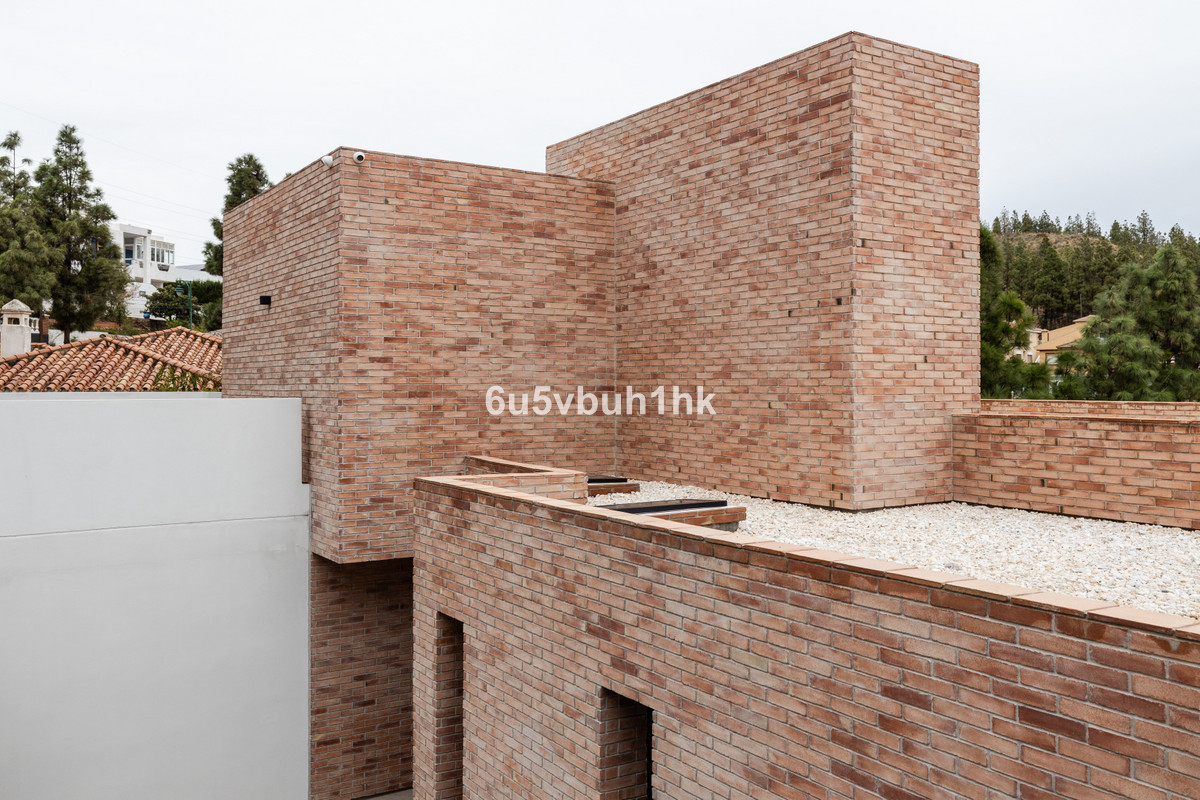 Modern bakstenen exterieurontwerp met witte stenen dakbedekking en witte wanden.