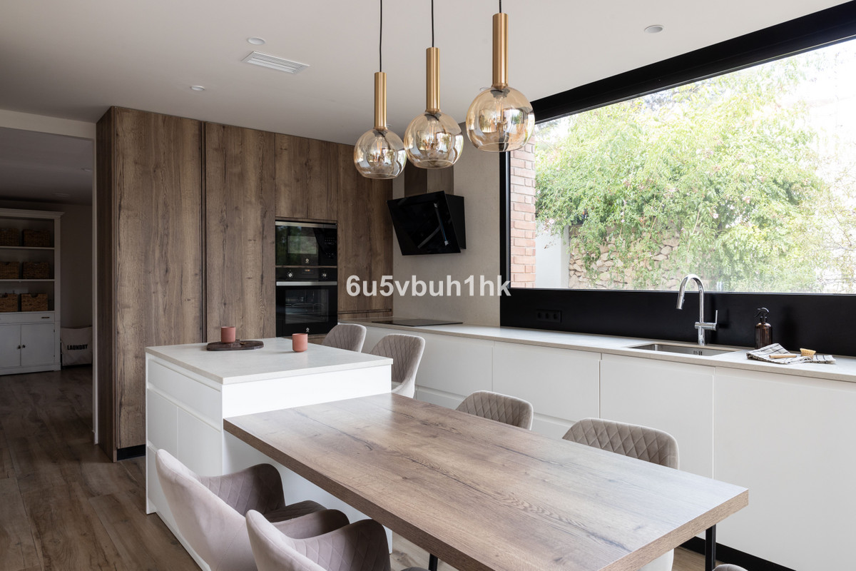 Moderne keuken met houten eettafel en groot raam.