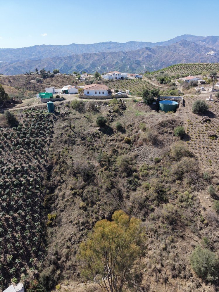 Aerial view of a hillside property with mountain backdrop and rural landscape
