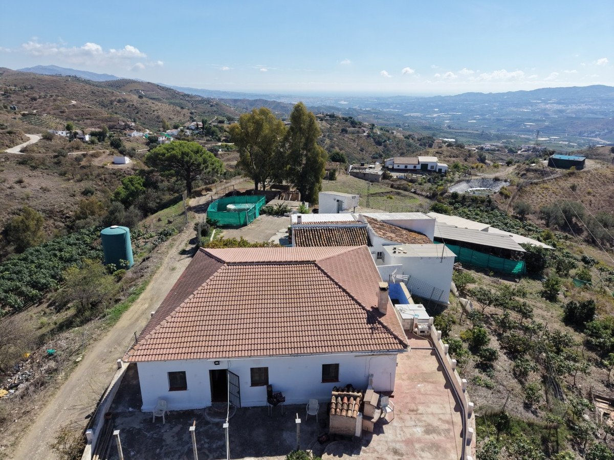Aerial view of a white country house with mountain views and surrounding landscape.