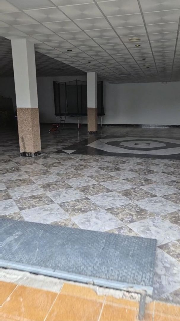 Spacious indoor area with checkered flooring, columns, and a trampoline visible in the background.