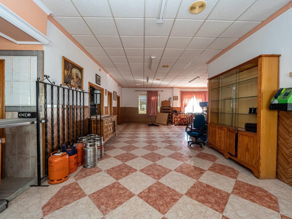 Spacious bar area with a checkered floor, wooden cabinets, and gas cylinders, suitable for a commercial establishment or event space.