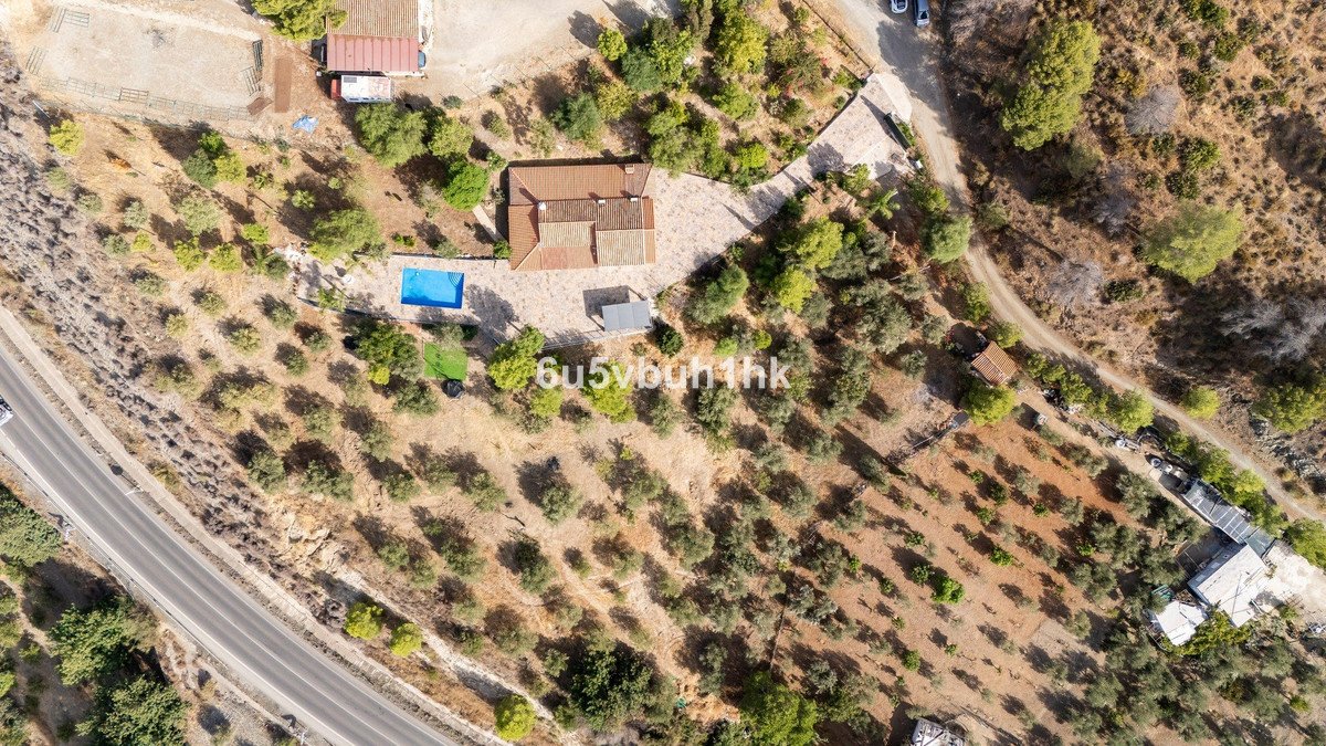 Aerial view of a villa with a swimming pool, surrounded by olive trees and a hilly landscape. Outdoor living space visible.