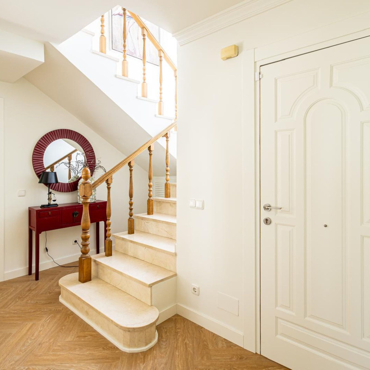 Entree met trap, rode console en spiegel.