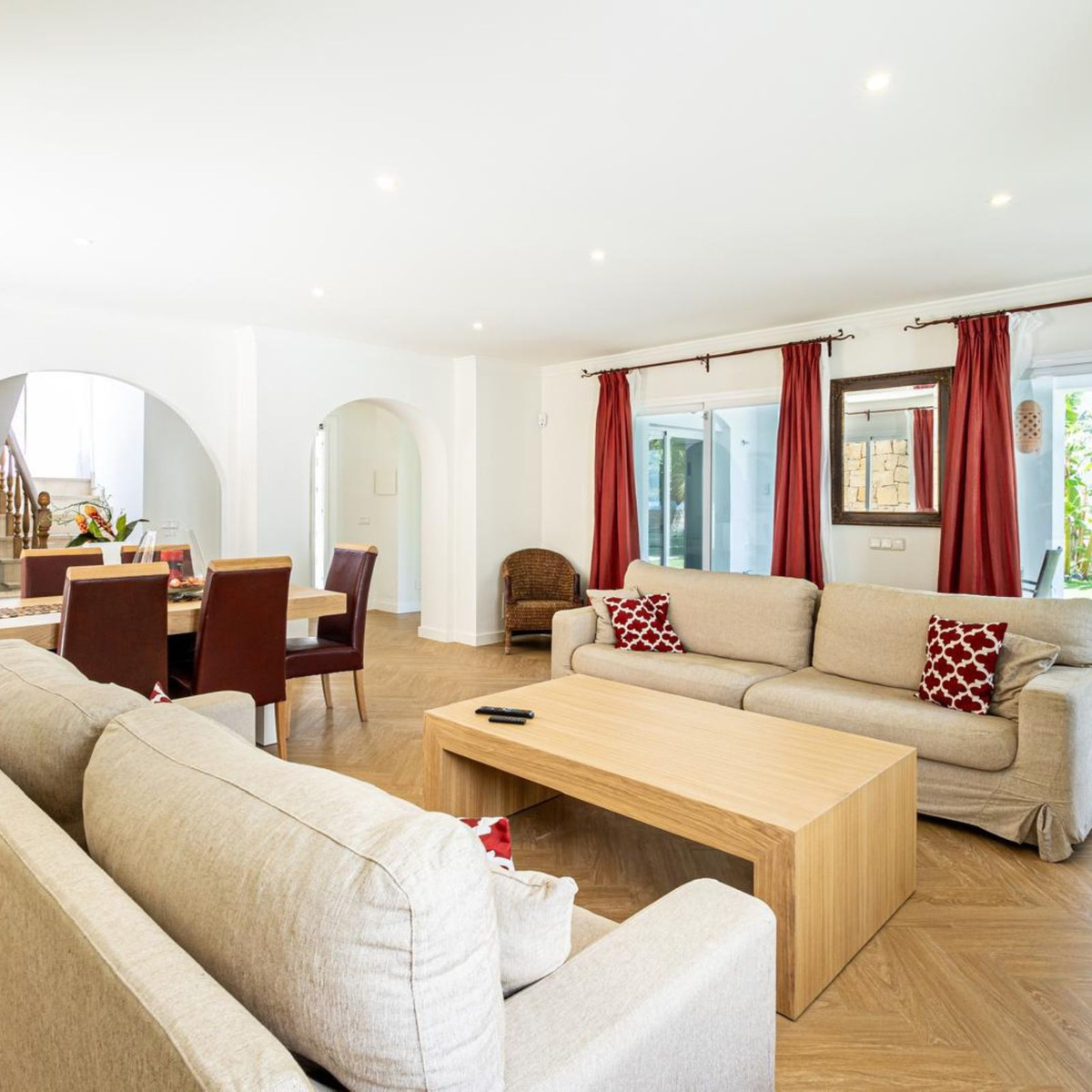 Elegante woon- en eetkamer met beige banken en rode accenten.