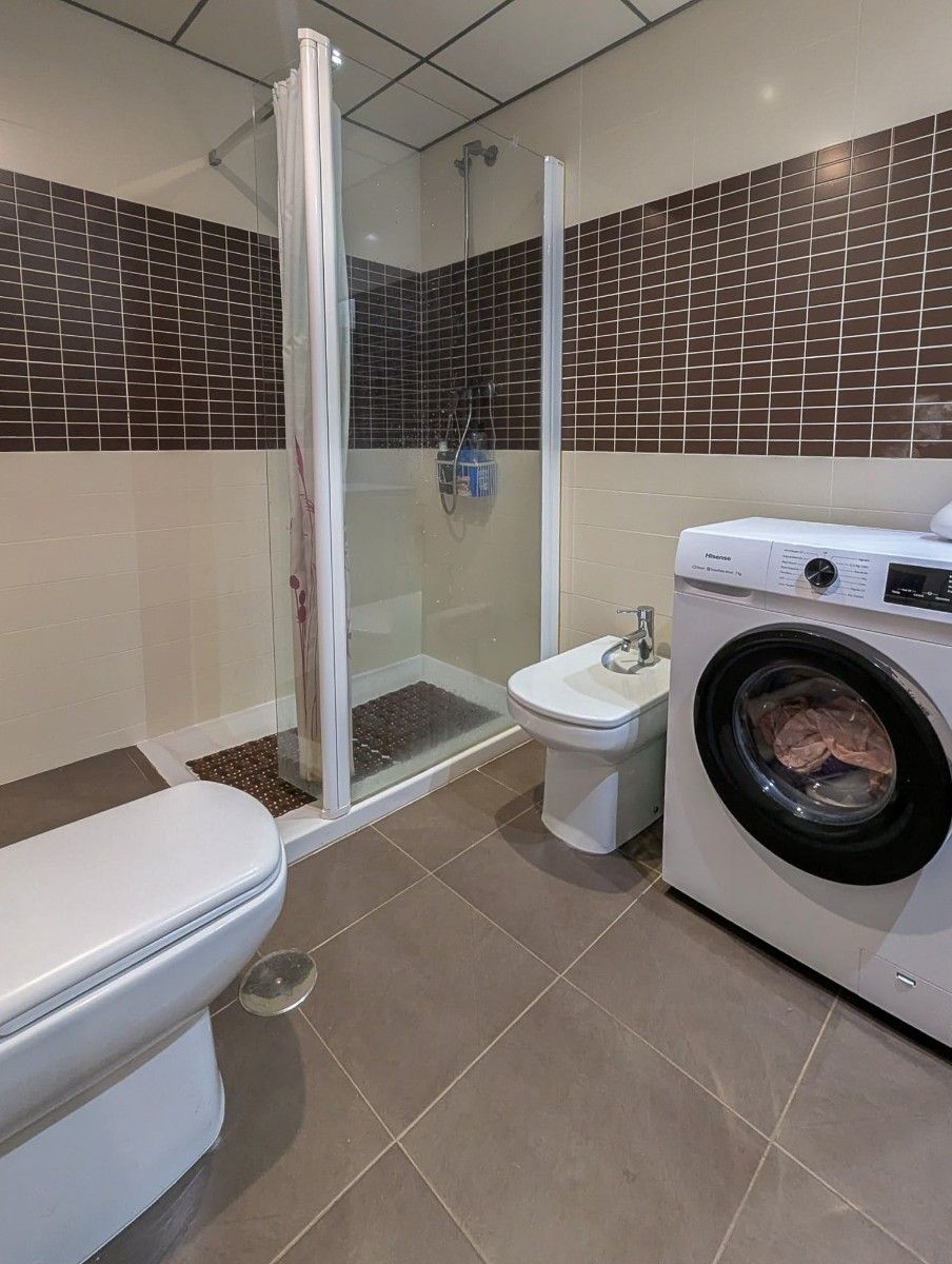Moderne badkamer met douche, bidet en wasmachine.