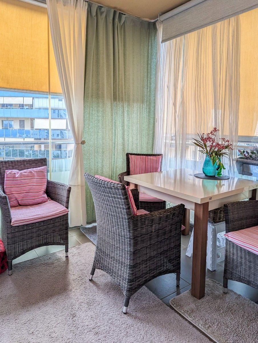 Balkon met eettafel, rieten stoelen en uitzicht op de stad.