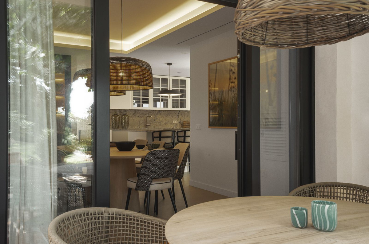 Modern interieur van een eetkamer met houten tafel en rotan lampen.