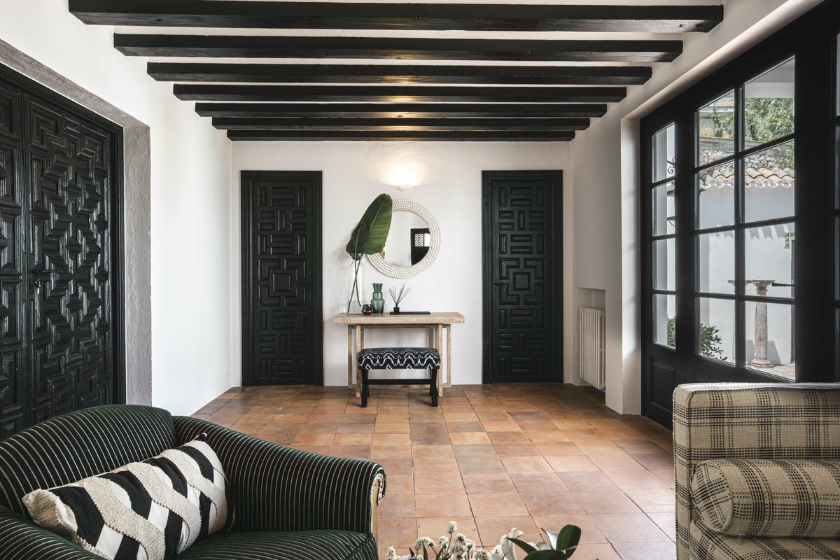 Stijlvol interieur met donkere houten deuren, houten balken plafond en terracotta vloer.