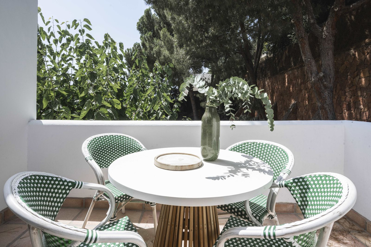 Terras met ronde tafel, groene stoelen en planten