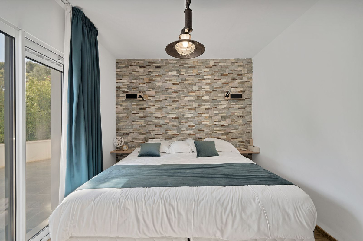 Stijlvolle slaapkamer met stenen muur en groot bed.