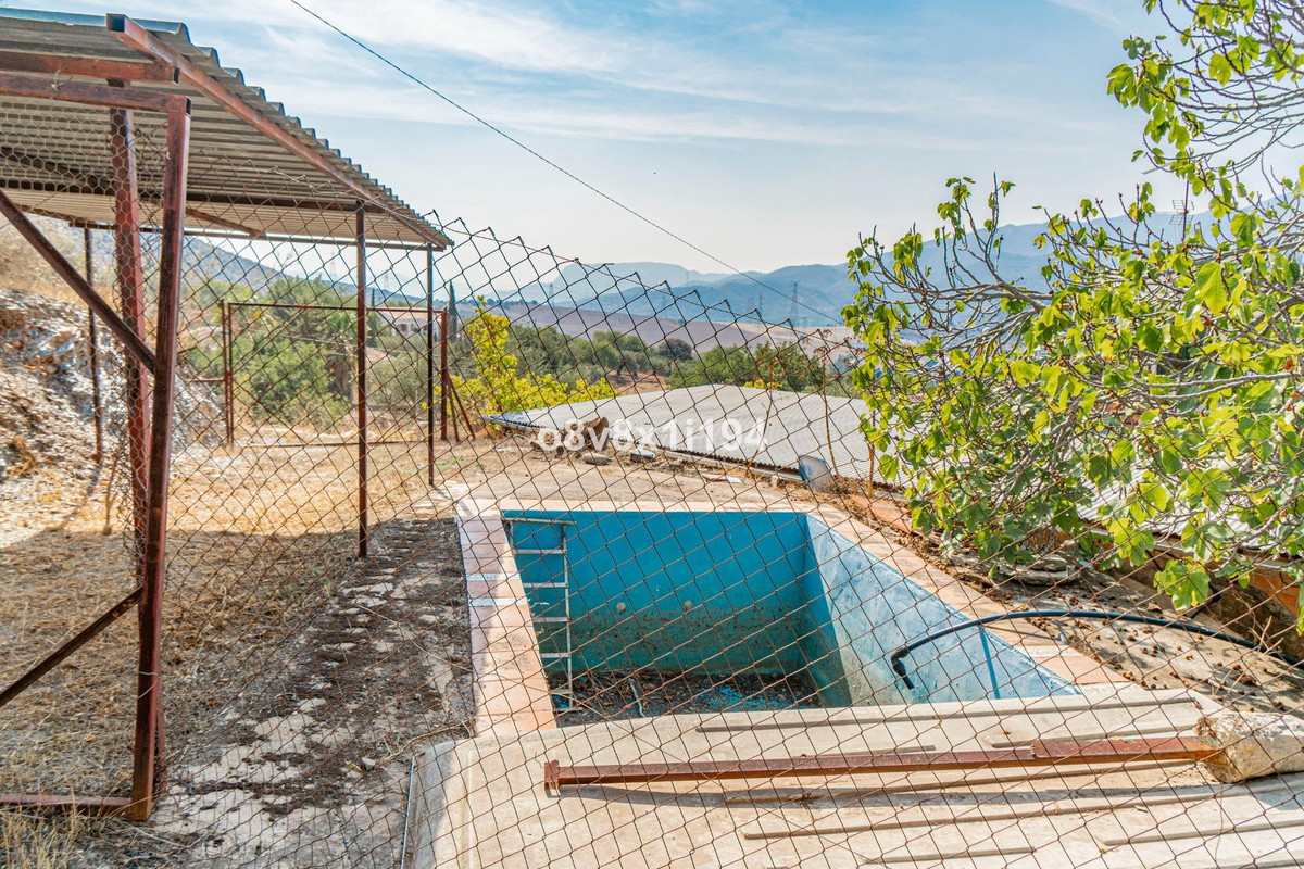 Verlaten zwembad op landelijk gelegen terrein, omheind met hekwerk.