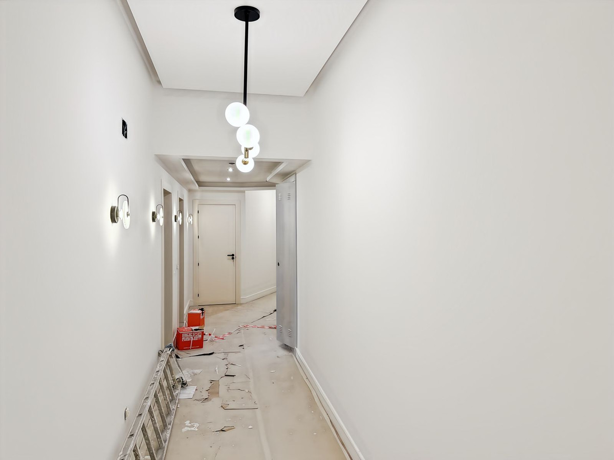 Halinterieur in renovatie, met ladder, bouwmaterialen en moderne verlichting.