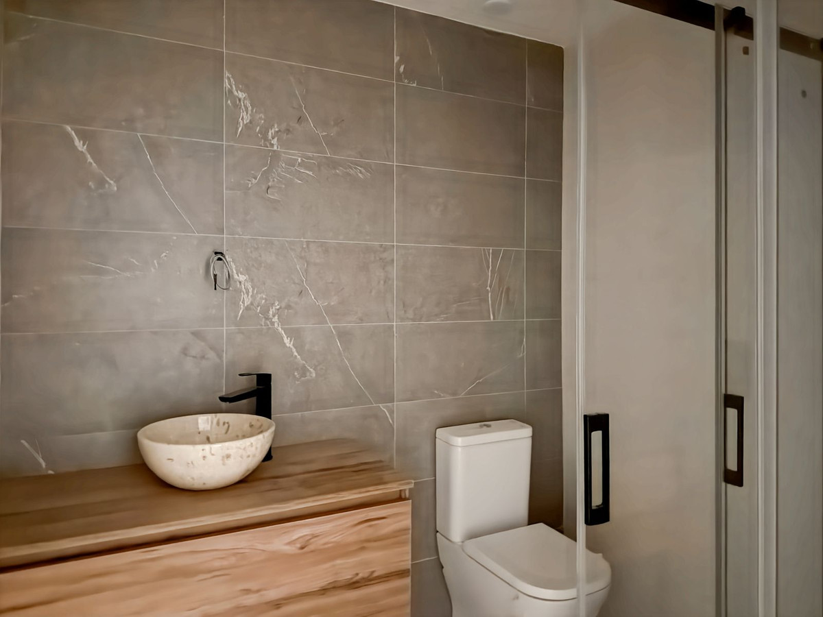 Moderne badkamer met houten kast en grijze tegels.