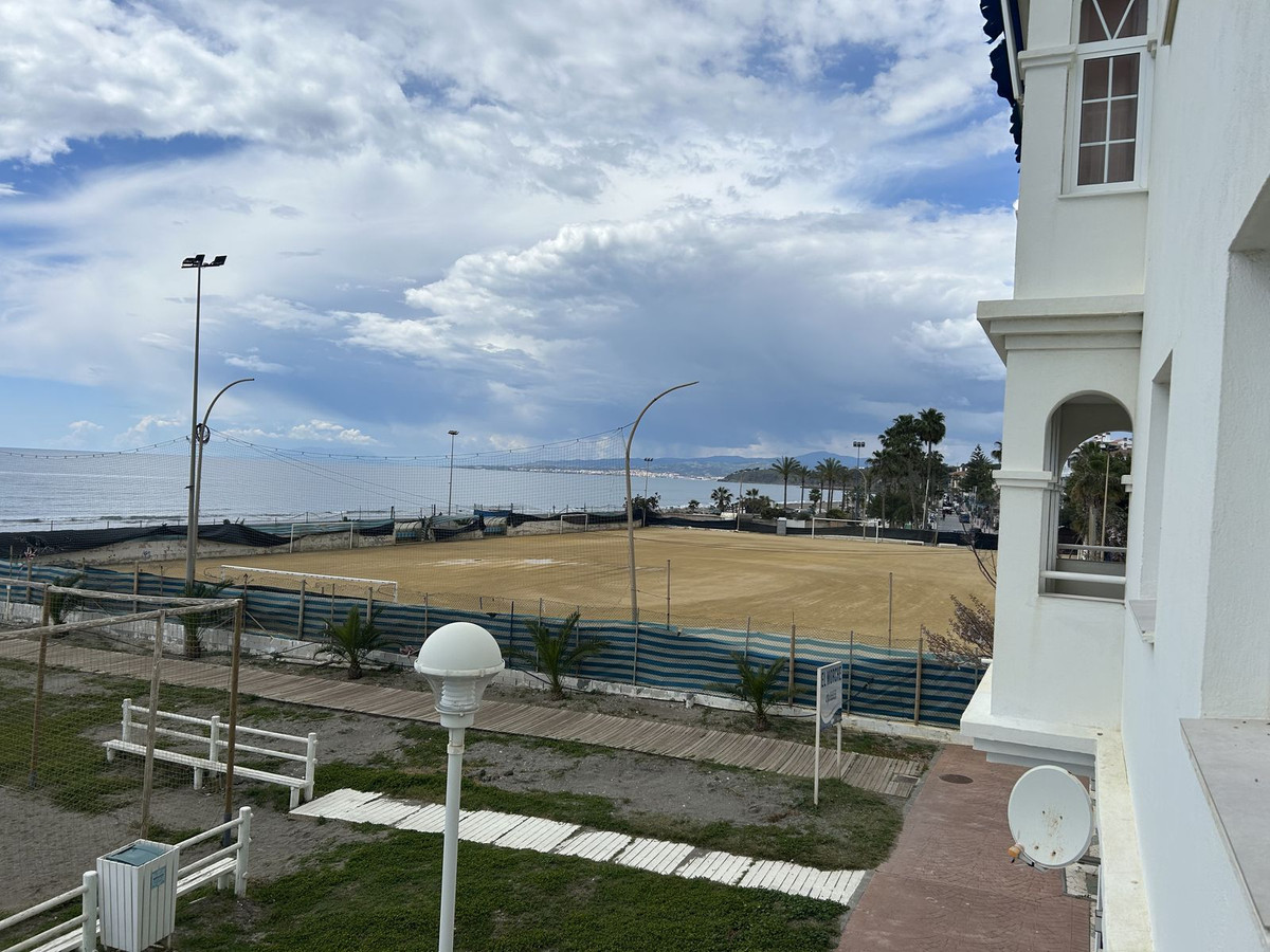 Uitzicht vanaf een wit gebouw op het strand met sportvelden.