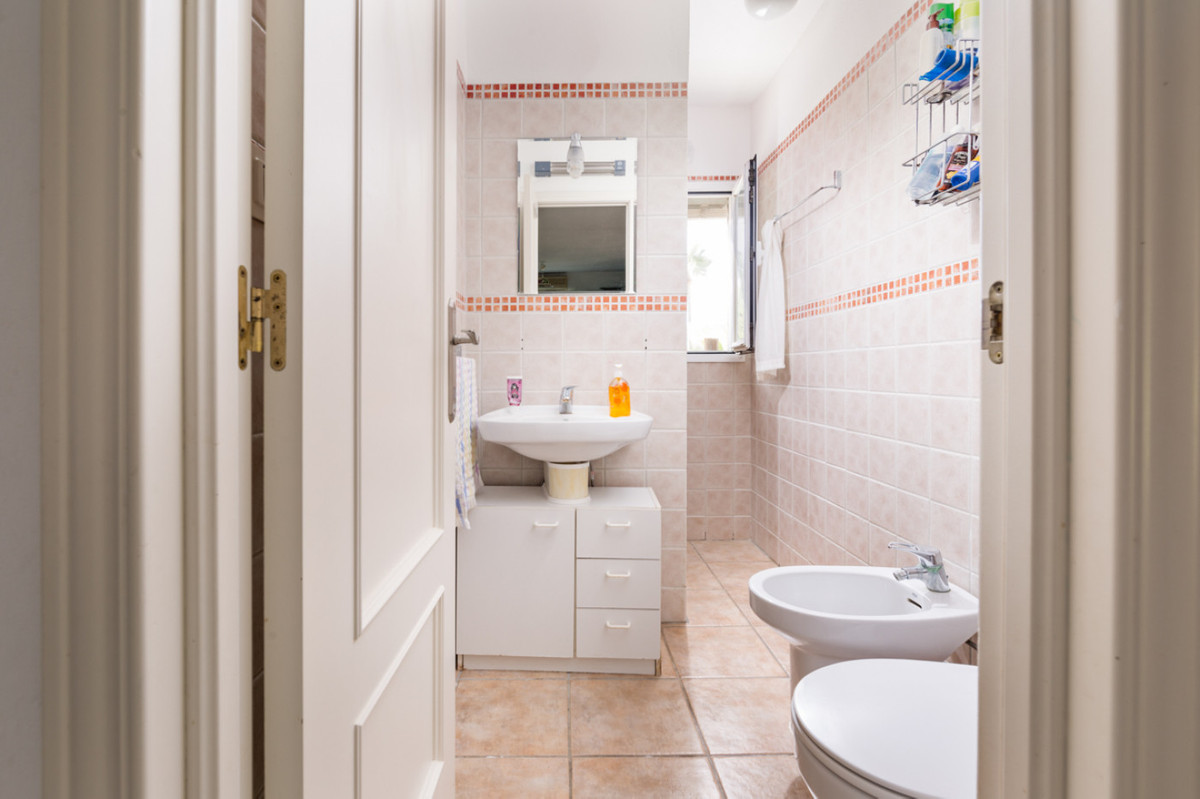 Badkamer met beige tegels, wit sanitair en natuurlijk licht via het raam.