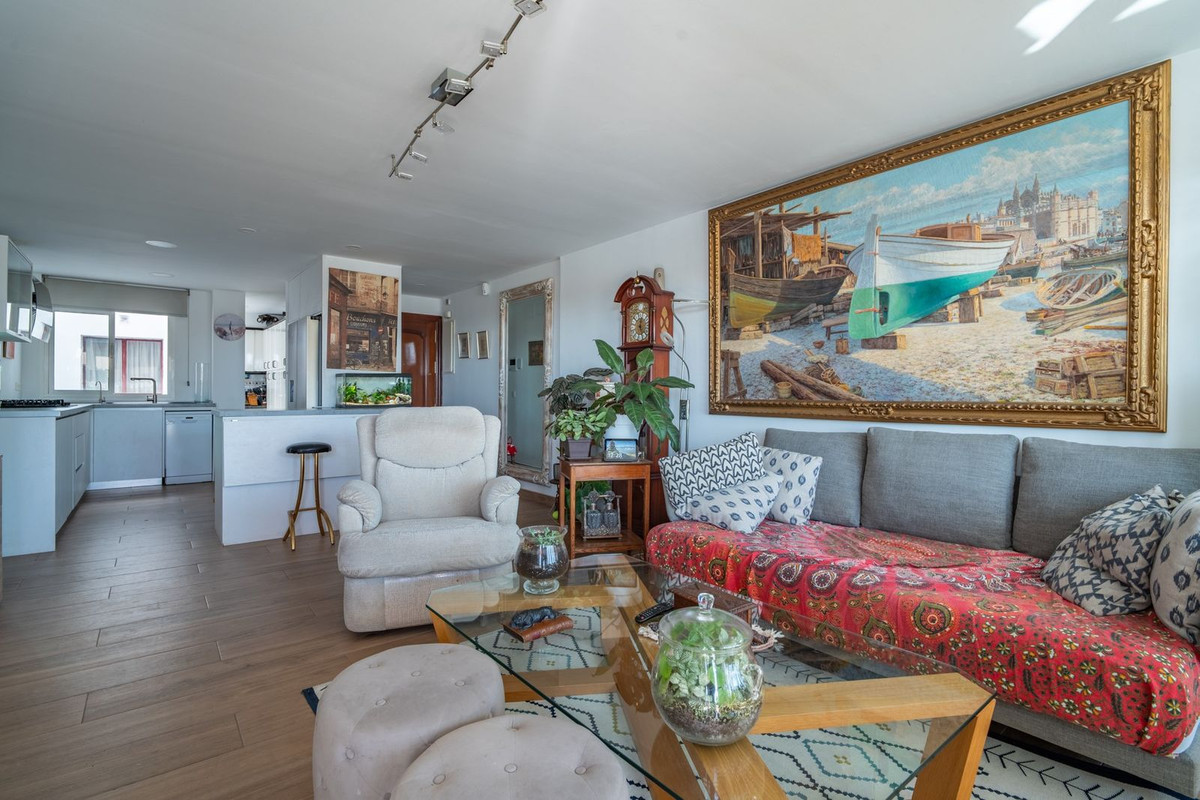 Lichte woonkamer met open keuken en kunst aan de muur.