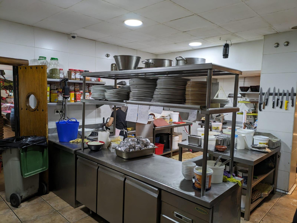 Restaurantkeuken met roestvrijstalen rekken vol borden en keukengerei.