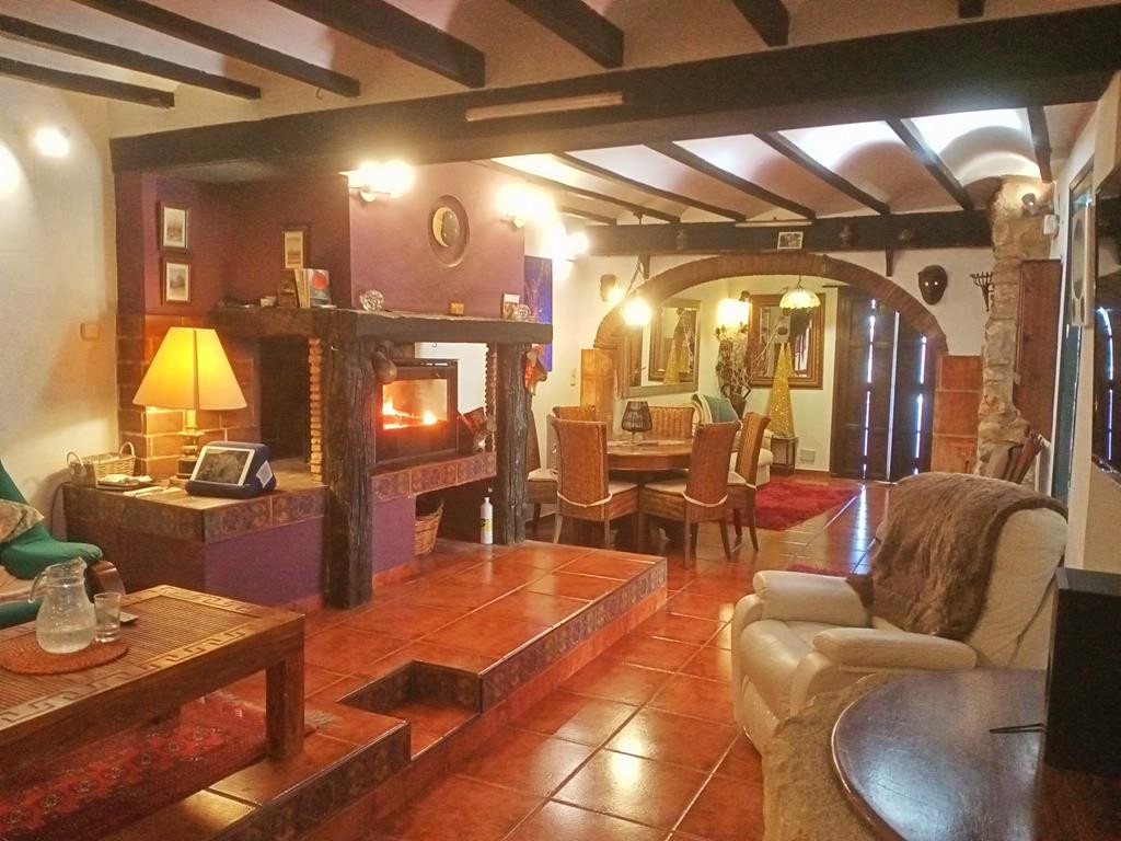 Cozy living and dining area with a fireplace, wooden beams, and tiled floors.
