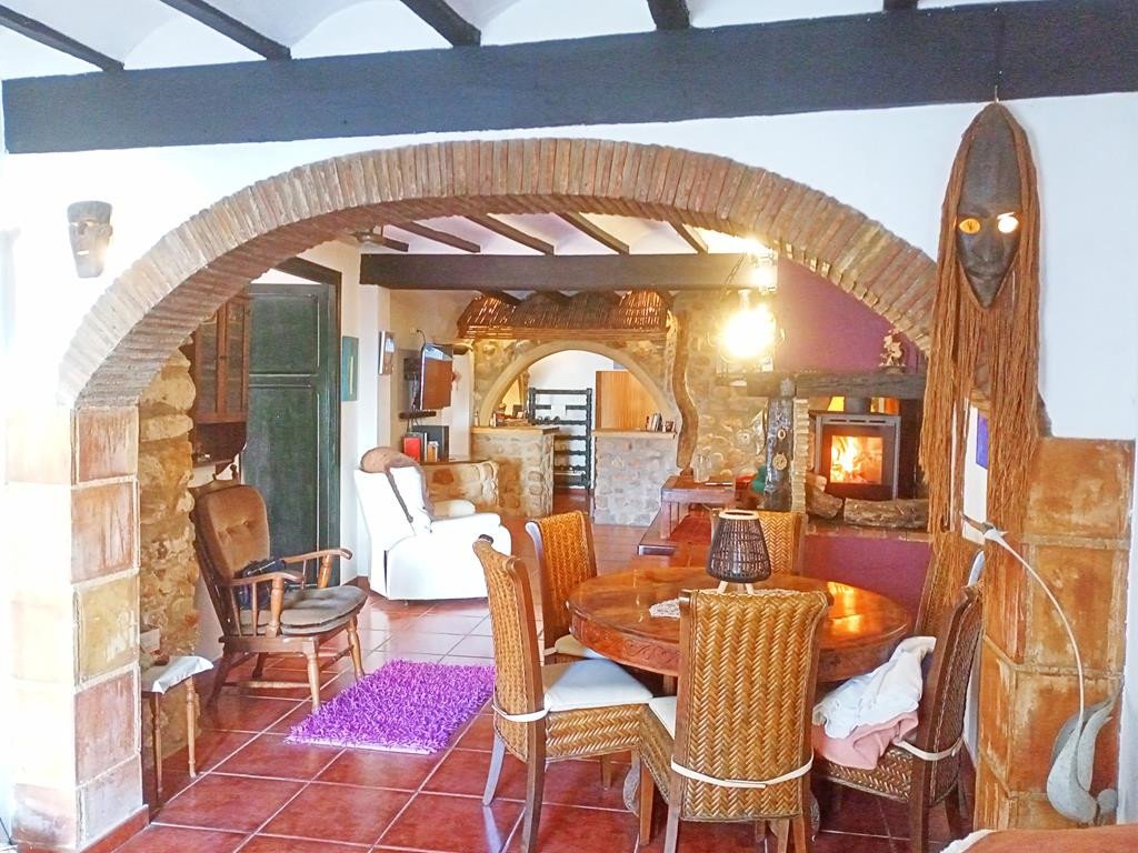 Cozy living and dining area with a fireplace, exposed brick archway, and rustic decor.