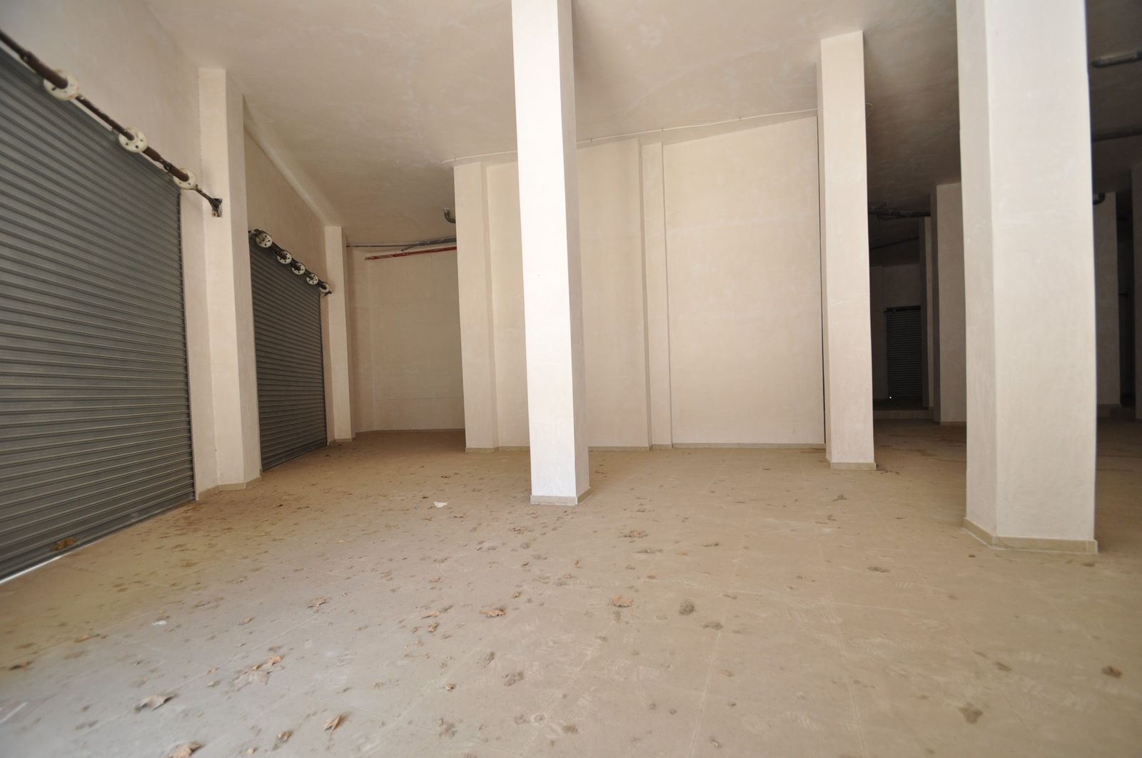 Lege commerciële opslagruimte met rolluiken en pilaren.