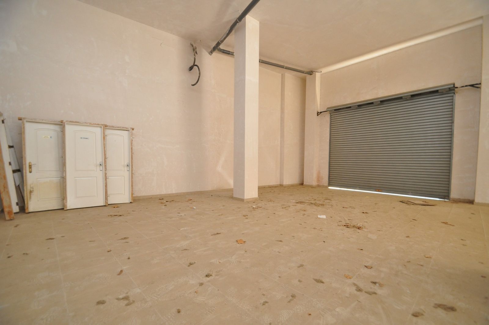 Onvoltooide commerciële ruimte met deuren en rolluik
