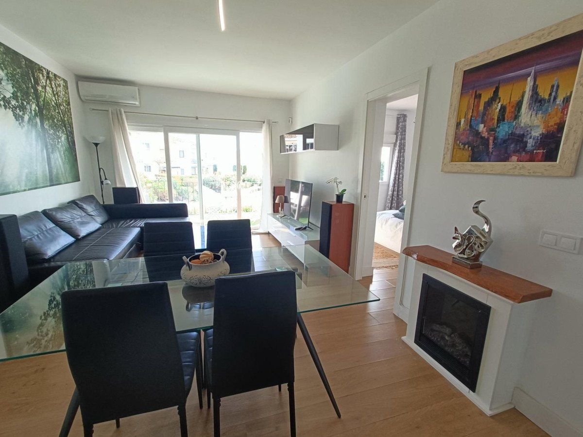 Living and dining area with black leather sofa, glass dining table, and a painting on the wall.