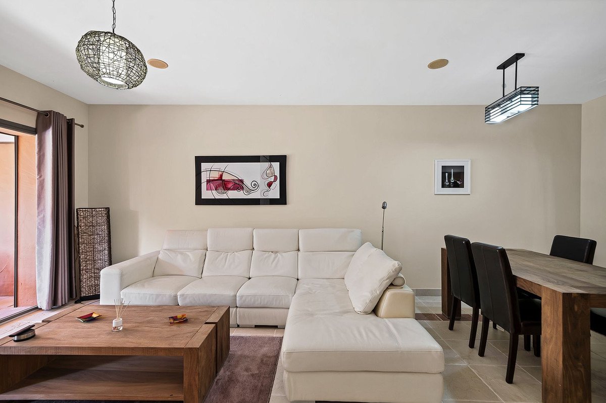 Modern living room with white sectional sofa, wooden coffee table, and dining area.