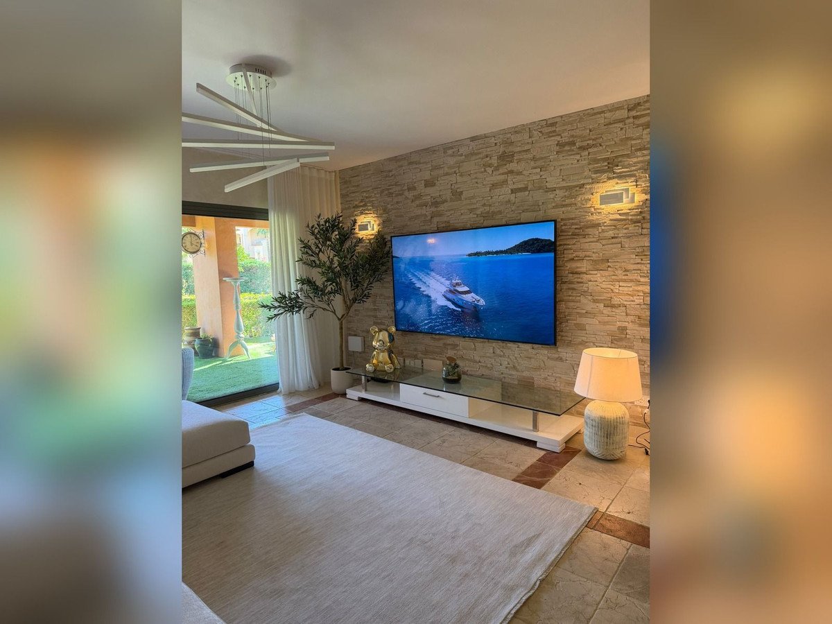 Modern living room with stone accent wall, large TV, and outdoor garden view