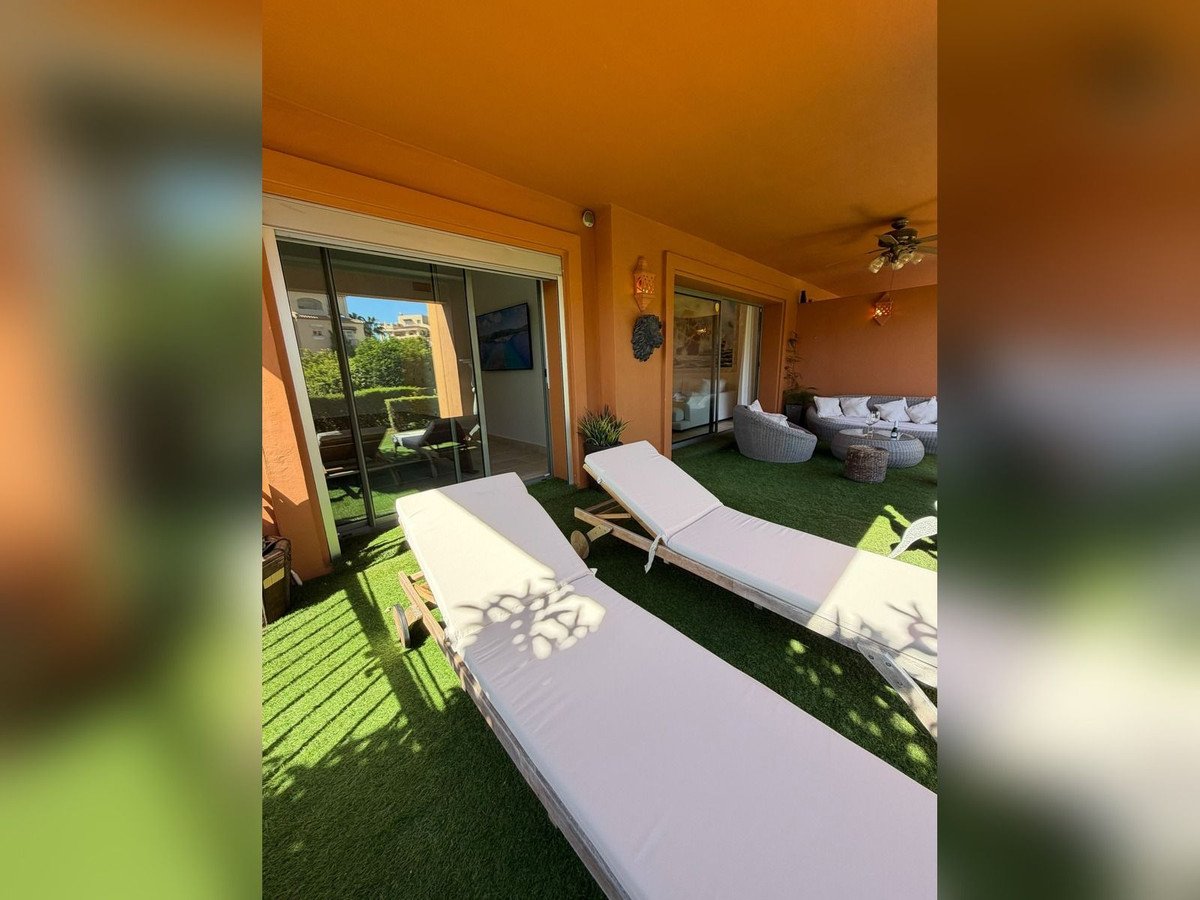 A terrace with sunbeds, lounge seating, and sliding glass doors to the interior.