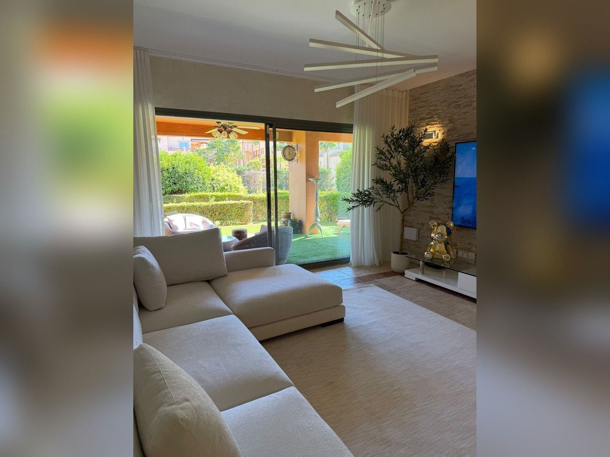 Modern living room with large sofa, sliding glass doors, and garden view