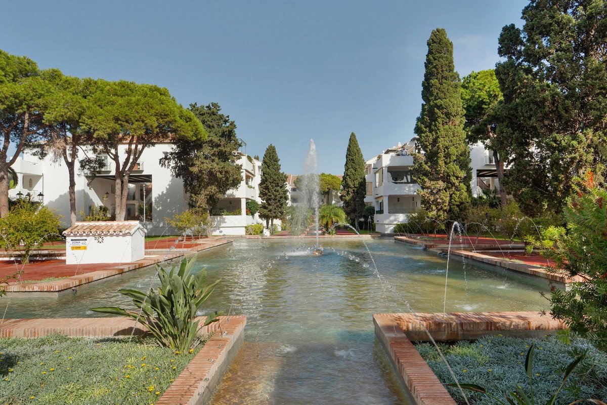 Resort pool with fountain and white buildings surrounded by trees