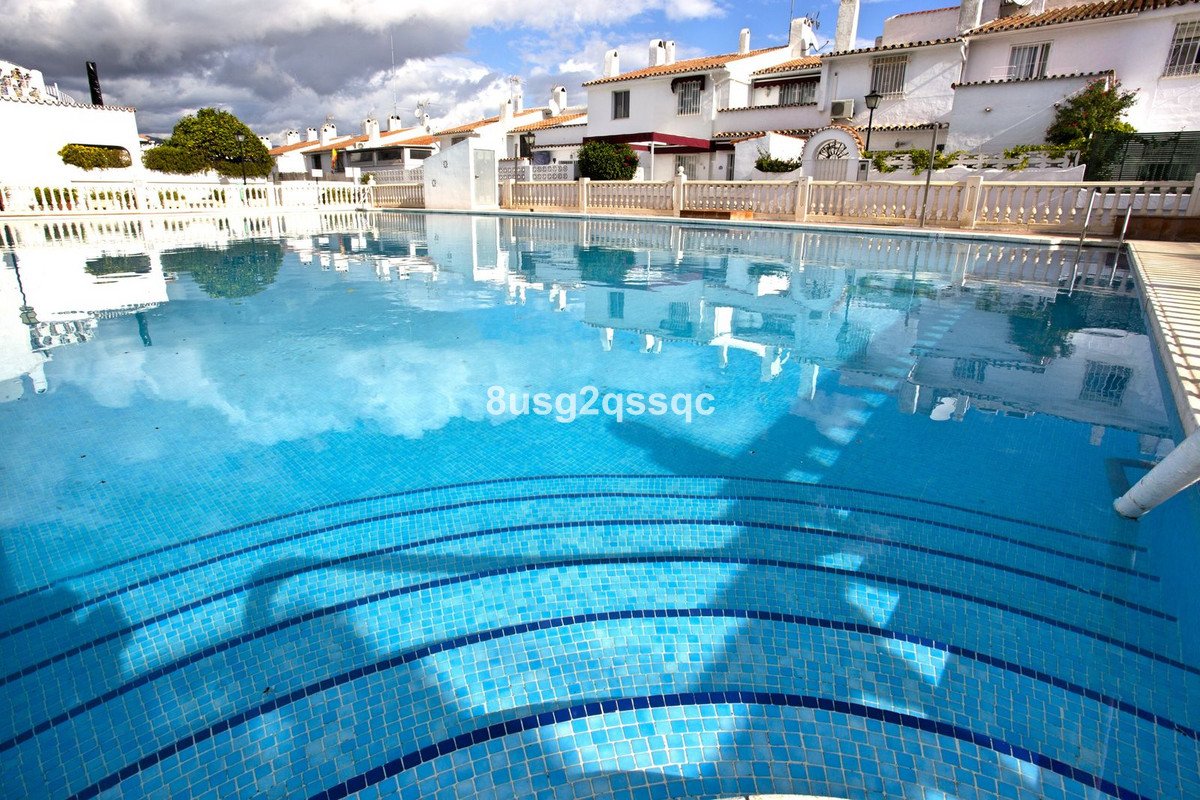 Community swimming pool with blue tiles and white houses in background