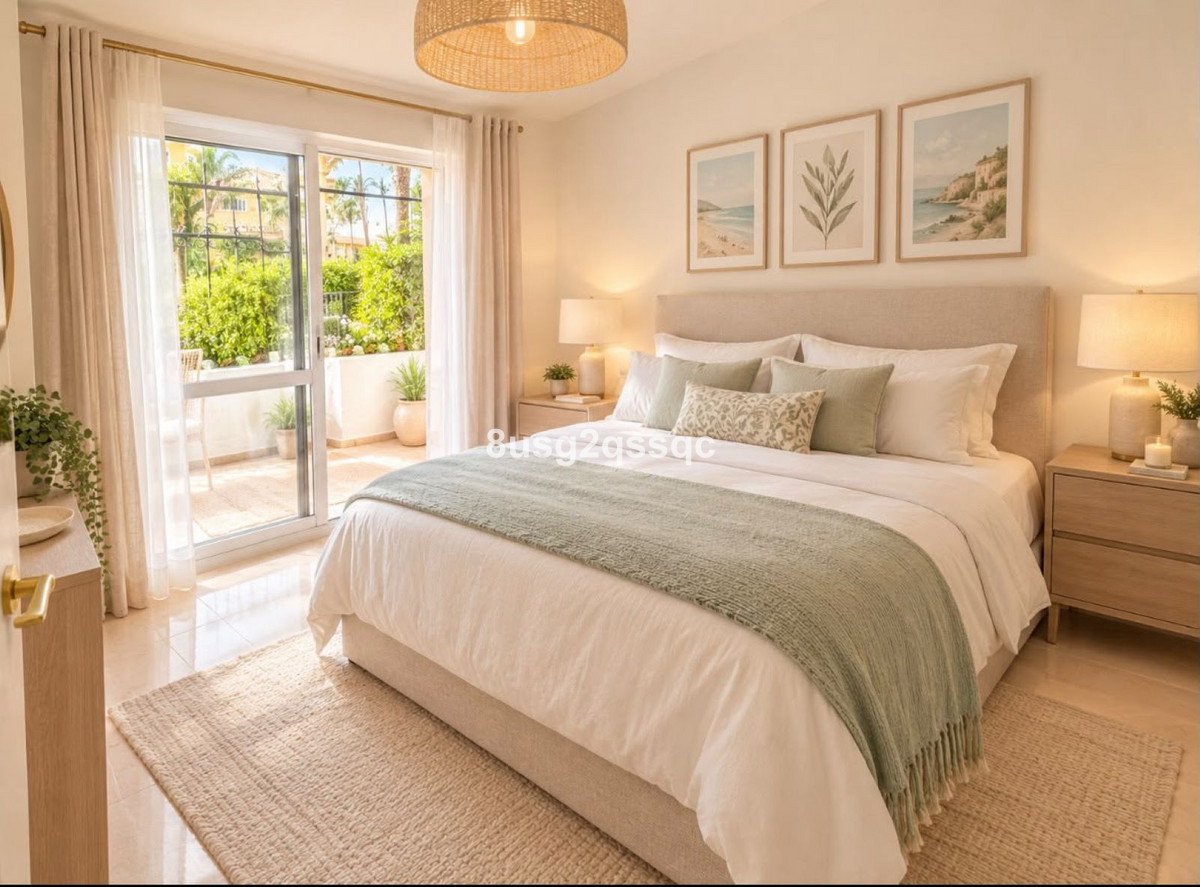 A cozy master bedroom with a large bed, bedside tables, and a balcony view of greenery.