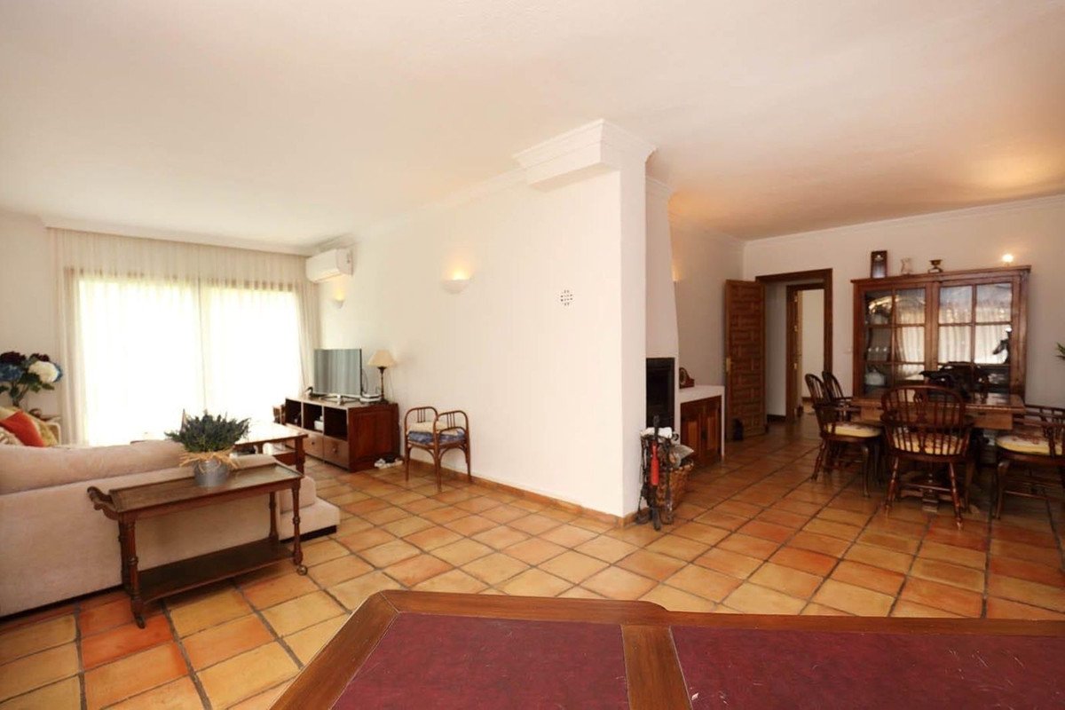 Spacious living and dining area with a fireplace, tiled floors, and a large window with curtains.