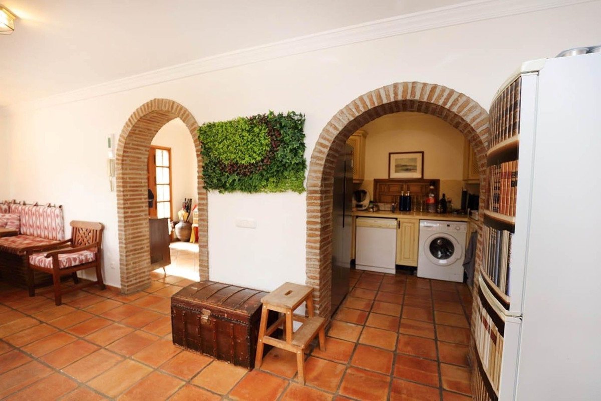 Interior view showing a living area with a sofa and a kitchen with arched entryways and a vertical garden.