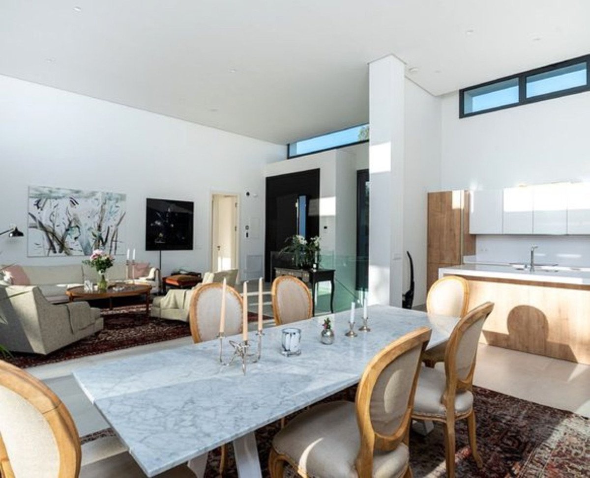 Spacious open-plan living, dining, and kitchen area with modern furniture, large windows, and a marble dining table.