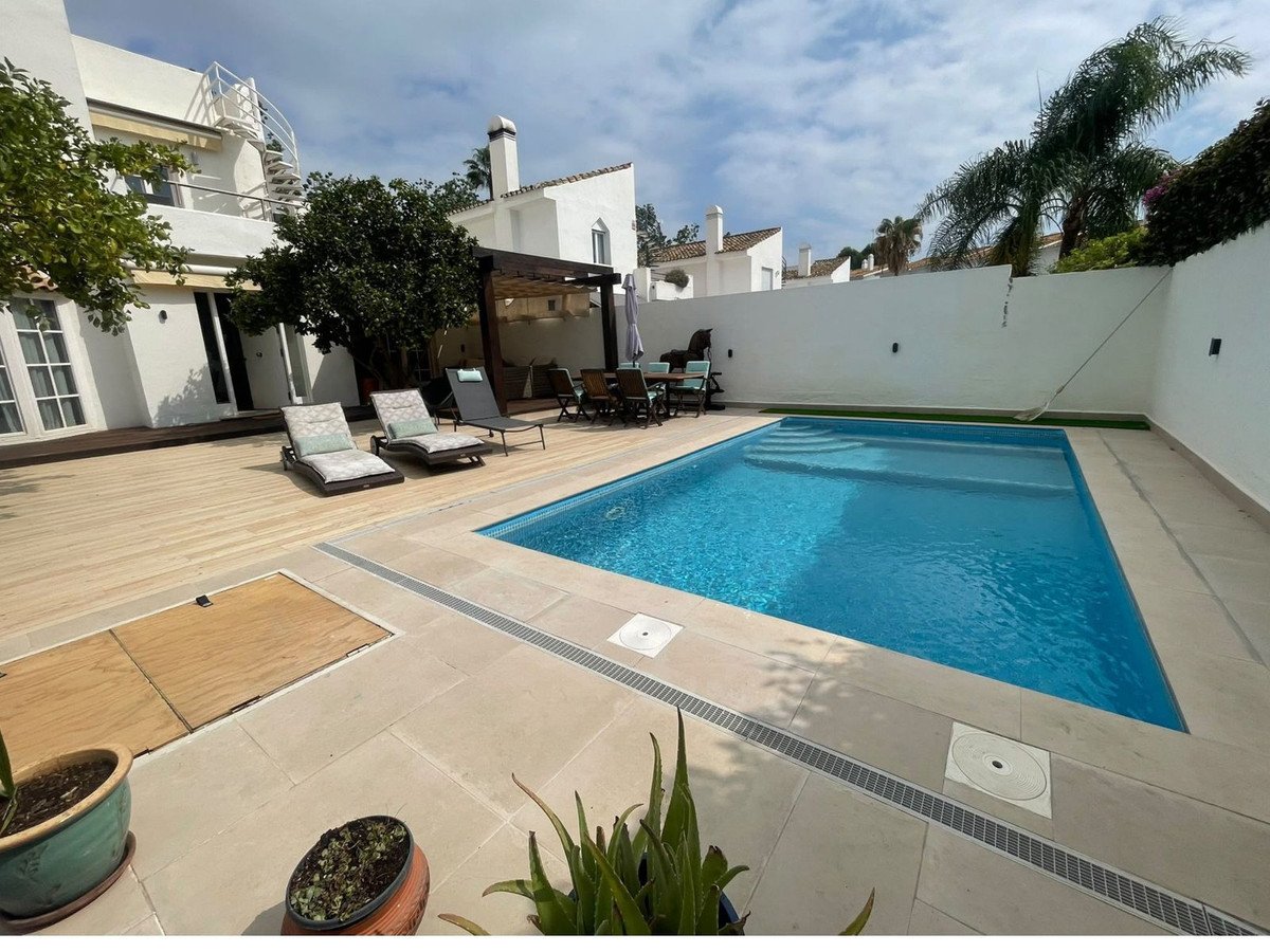 Villa backyard with swimming pool, sun loungers, and outdoor seating area